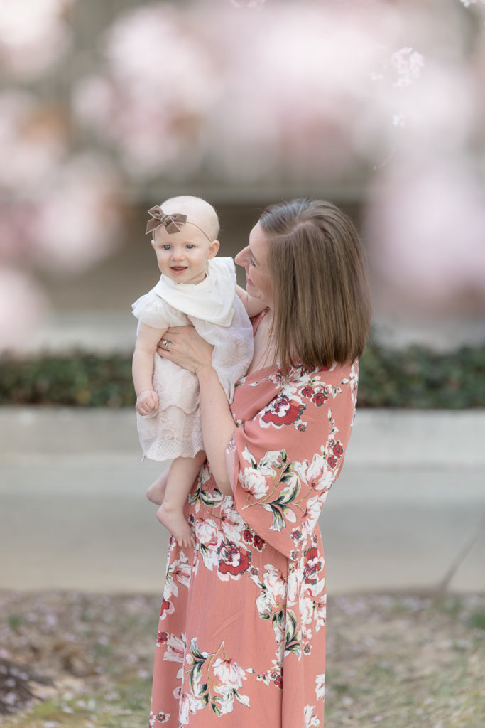 mom and baby giggle under cherry blossom blooms