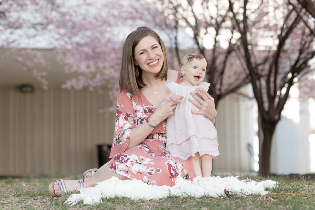 mom and baby sit under blooms and smile