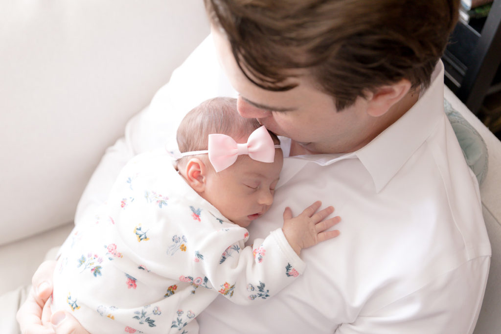 dad snuggles tiny newborn girl