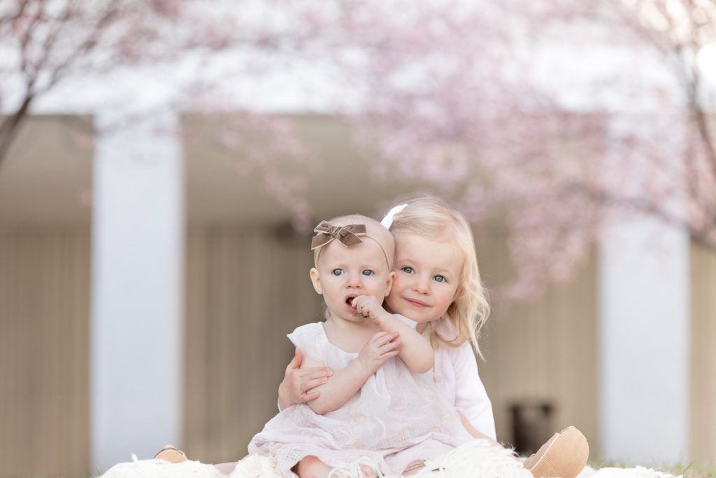 sisters snuggle under cherry blossoms