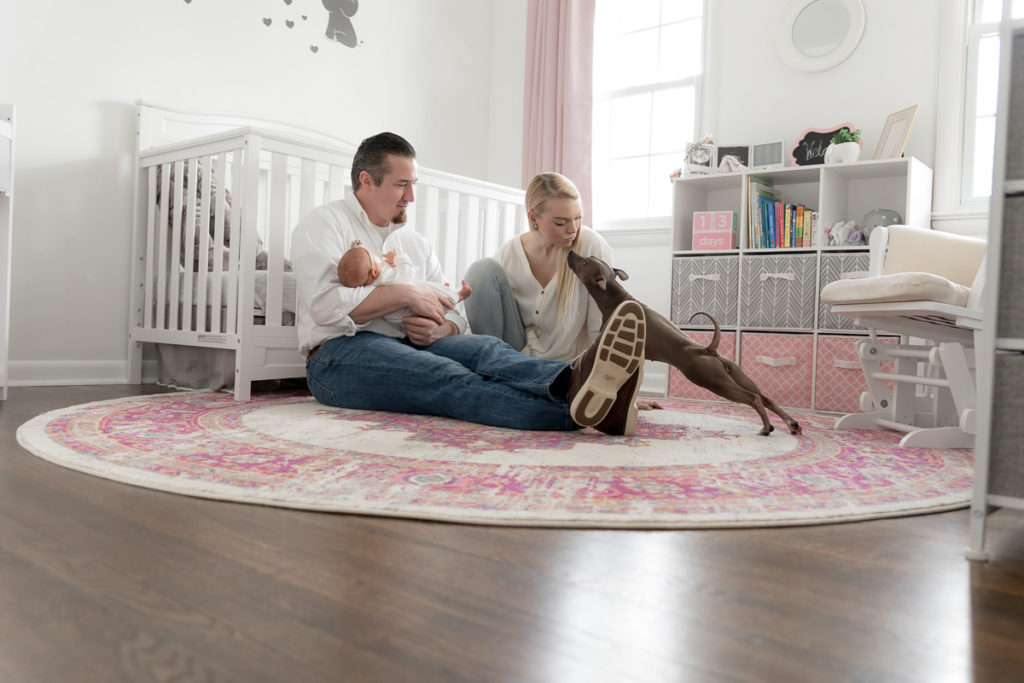 family sits on nursery floor with new babe