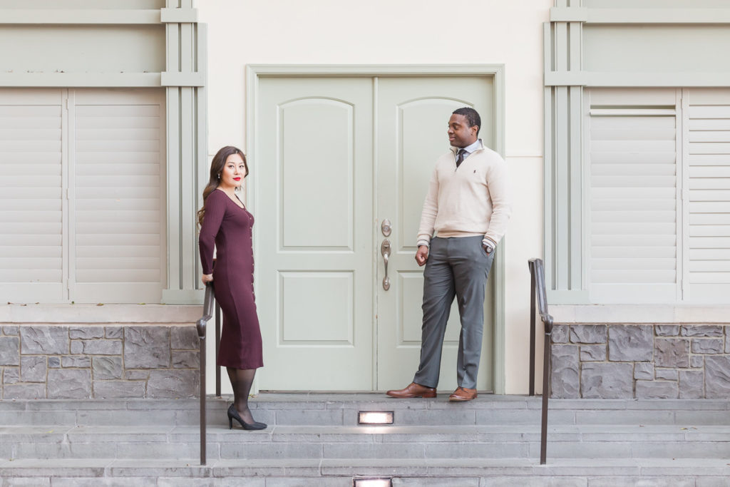 engaged couple posing on stairs next to door