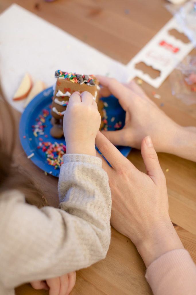 mom and daughter work together on gingerbread house