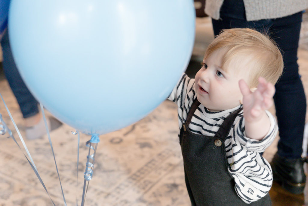 birthday boy grabs at a blue balloon