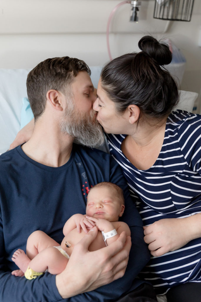 parents kiss over newborn's head