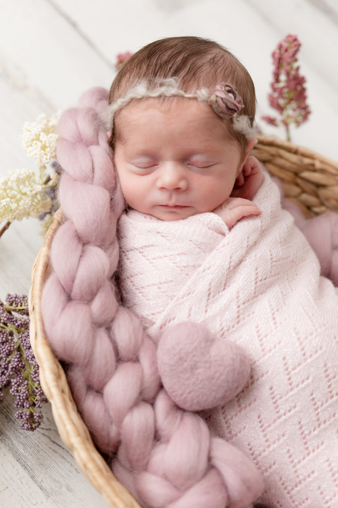 baby girl snuggles on pink blanket with pink felted heart