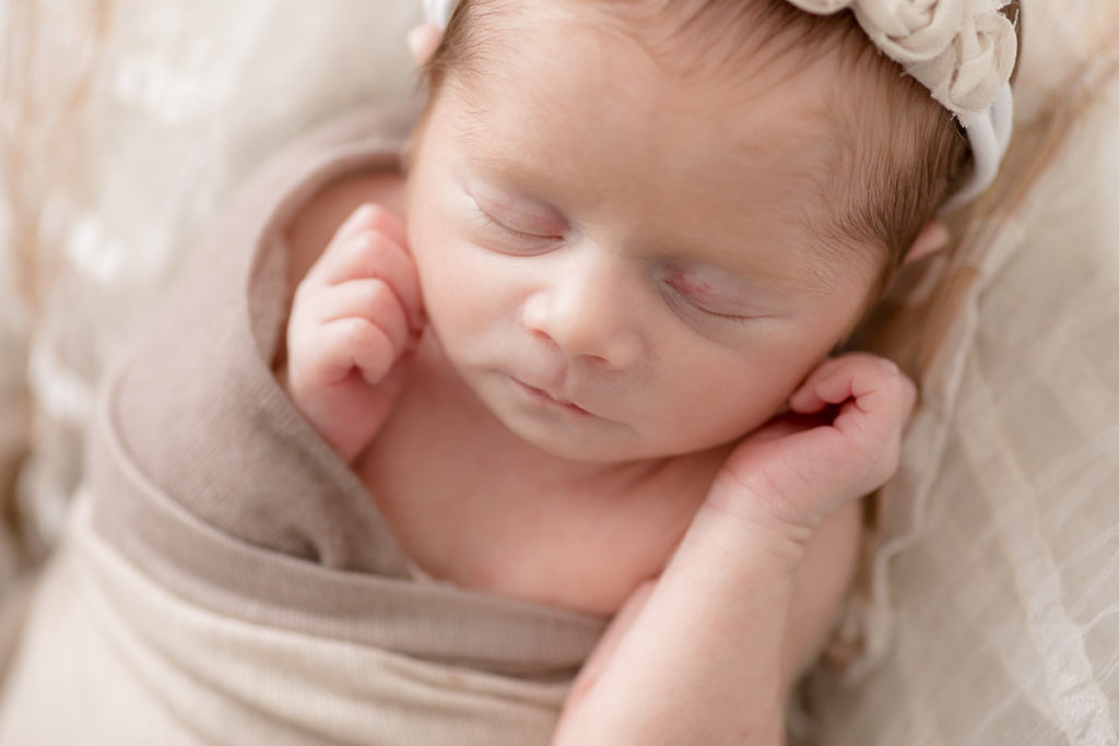 closeup shot of newborn with hands by face