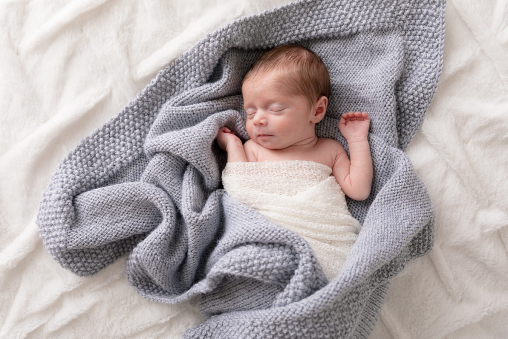 newborn girl snuggles in blue blanket
