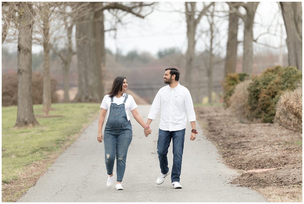 expectant couple walks down tree-lined street