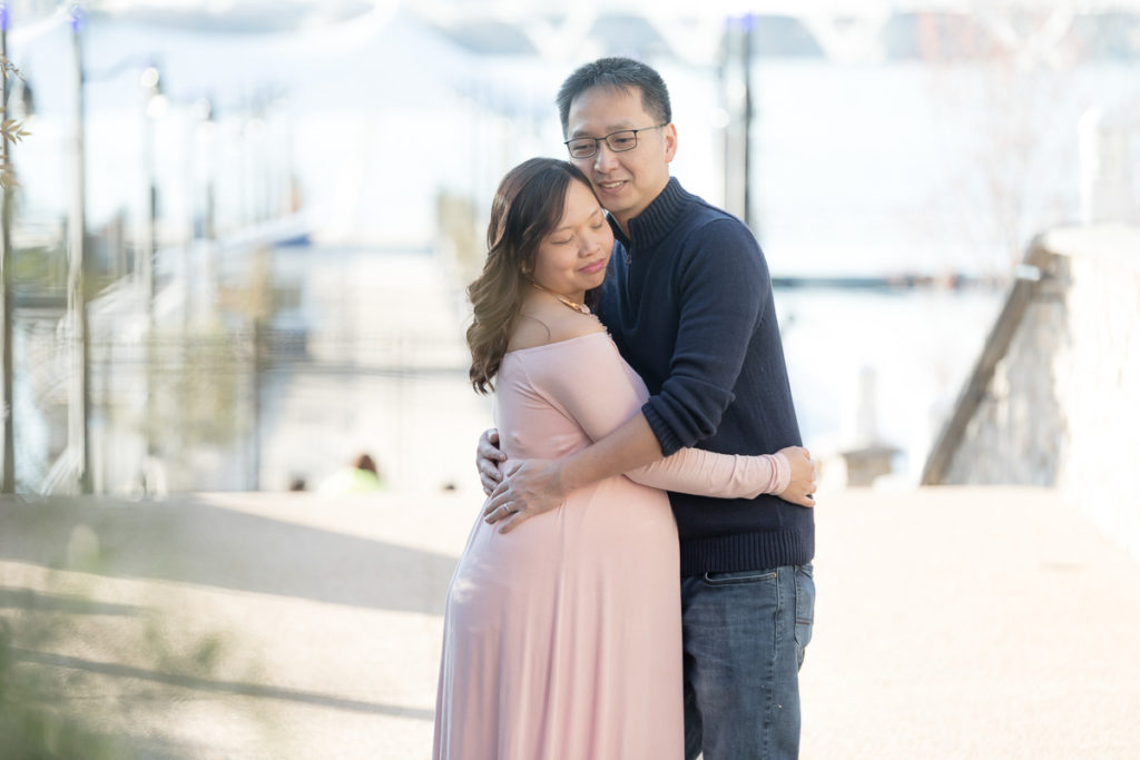 husband hugs pregnant wife at National Harbor steps