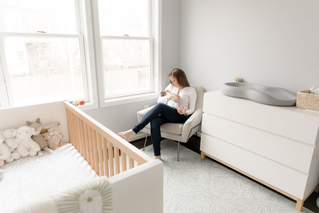 new mom snuggles son in light-filled nursery