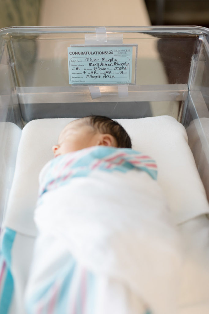 swaddled newborn in hospital bassinet