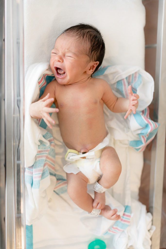 crying newborn in hospital bassinet