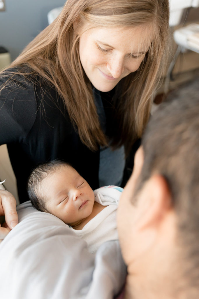 social distancing mom smiles proudly at newborn