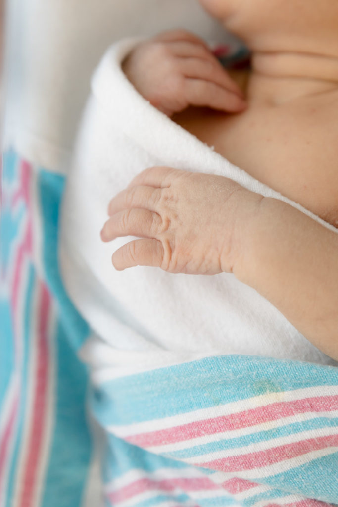 tiny newborn hands against hospital swaddle