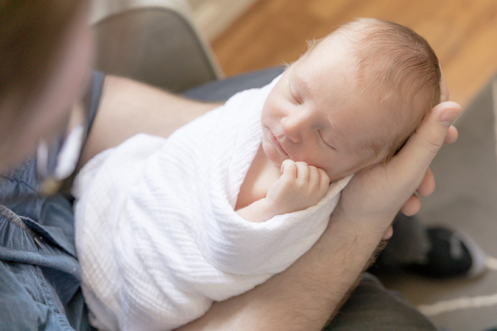 sleepy newborn boy in dad's hands