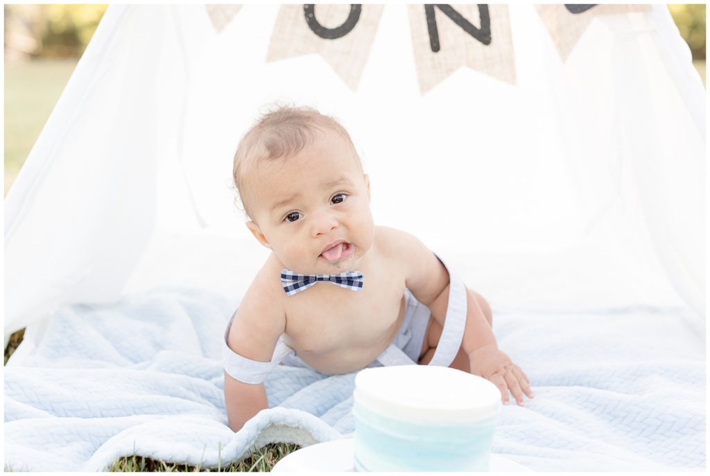 baby boy sticks his tongue out during cake smash session