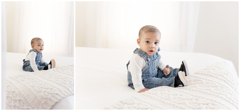 baby sitting on white bed in front of window