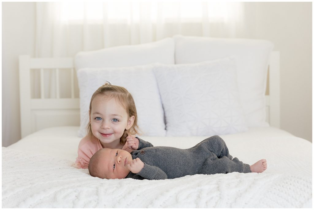 big sister, baby brother on white studio bed