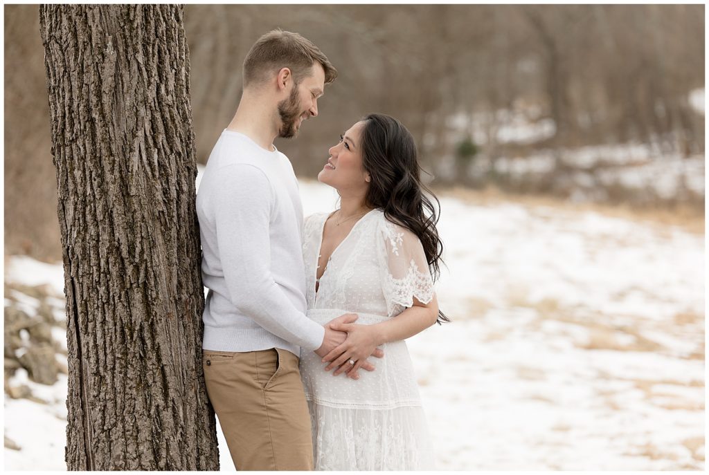 pregnant woman gazes up at husband during Winter Maternity Photos at the Howard County Conservancy