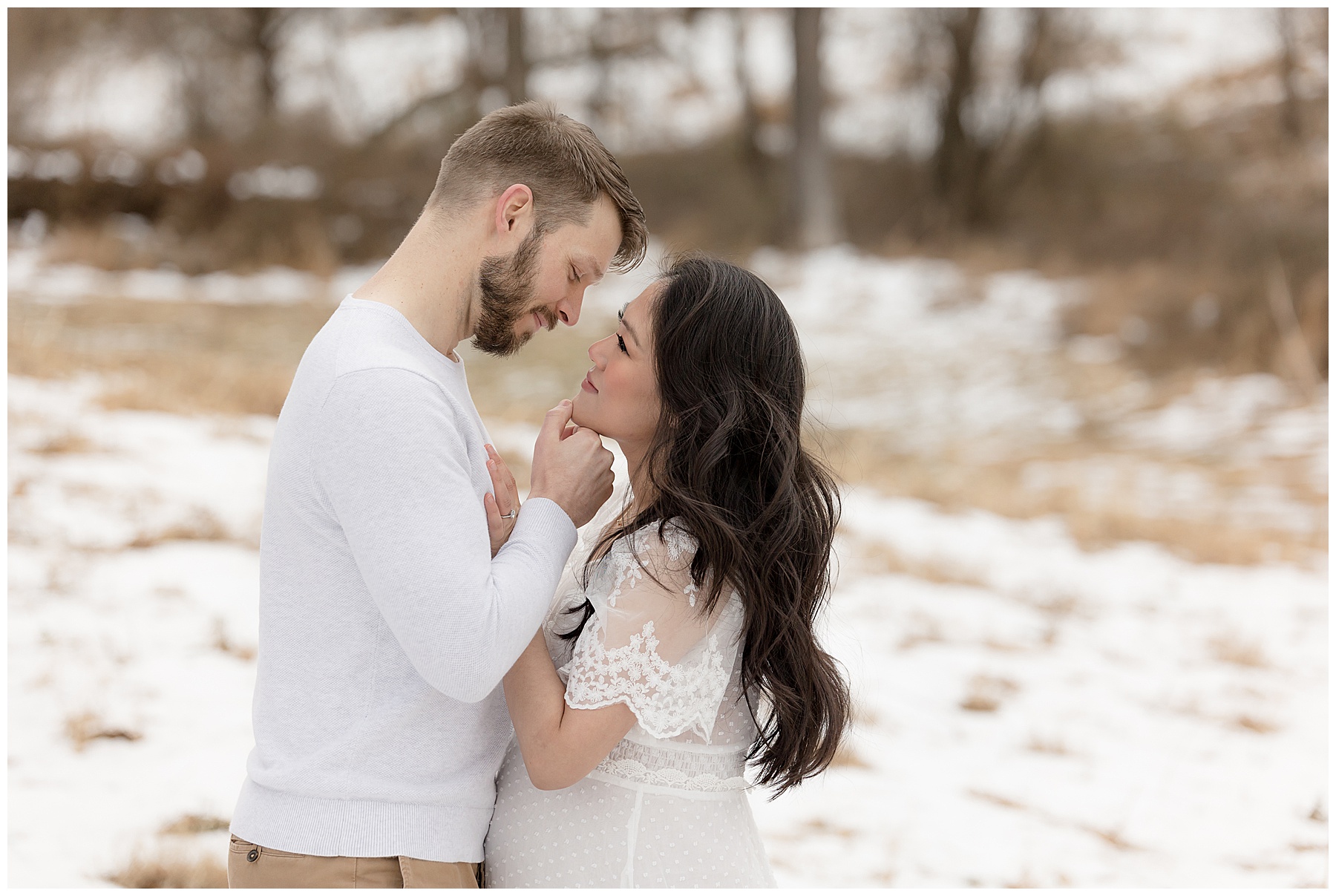 man tenderly holds wife's face during Winter Maternity Photos at the Howard County Conservancy