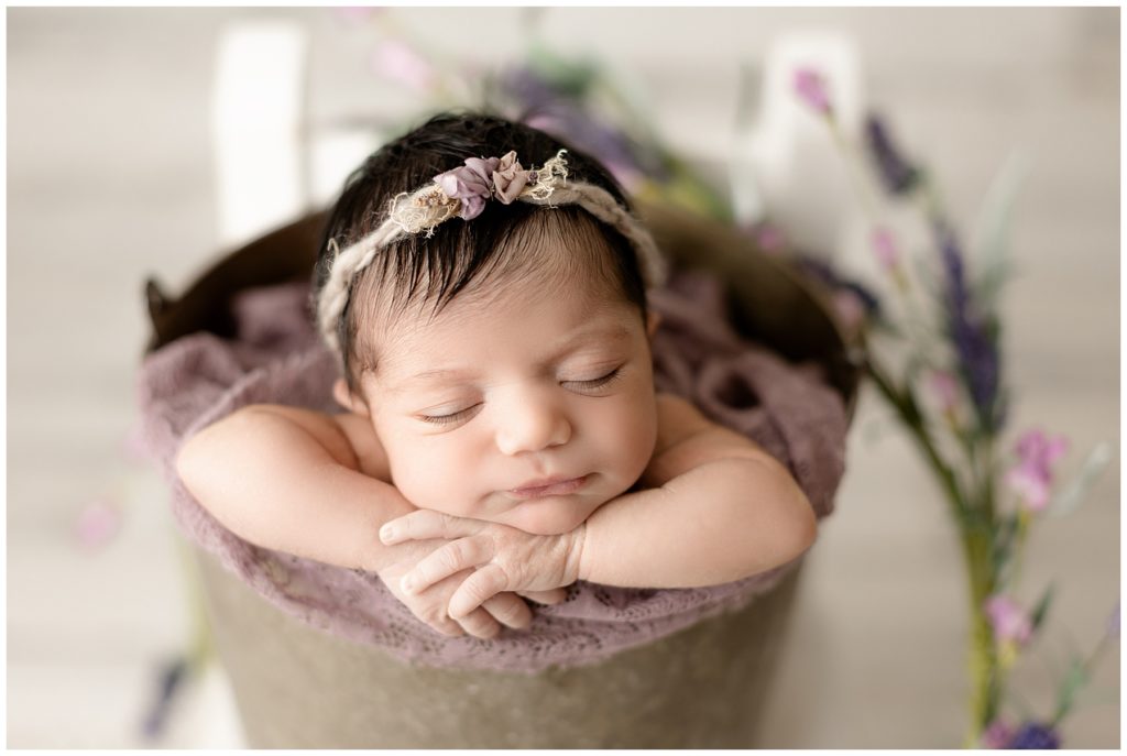 newborn posing in a bucket with flowers