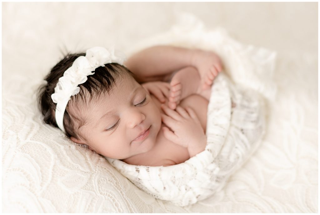 newborn girl in cream wrap and headband