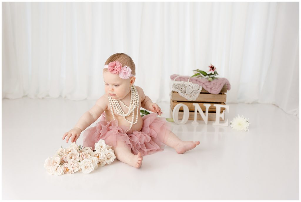 baby in pink tutu reaches for white roses