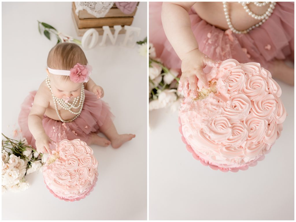 baby puts hand in pink roses smash cake