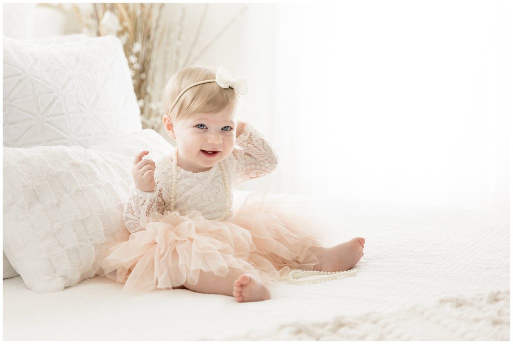 blue eyed baby giggles on white bed photo backdrop