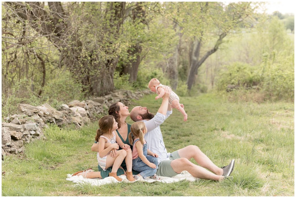dad flies baby while mom and sisters look on