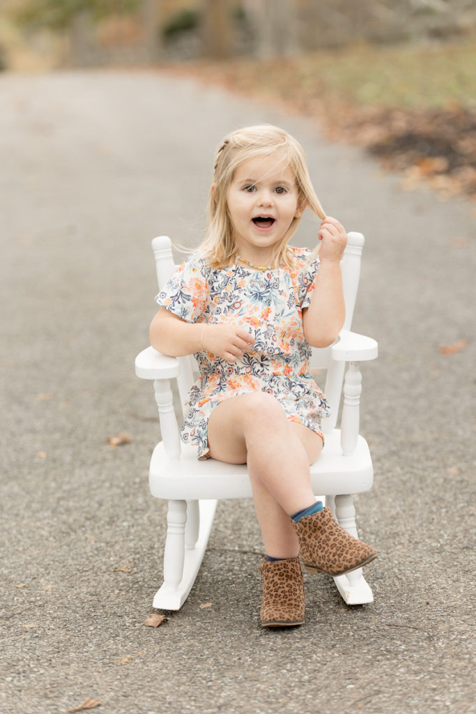 blonde toddler crosses legs and sits in rocking chair
