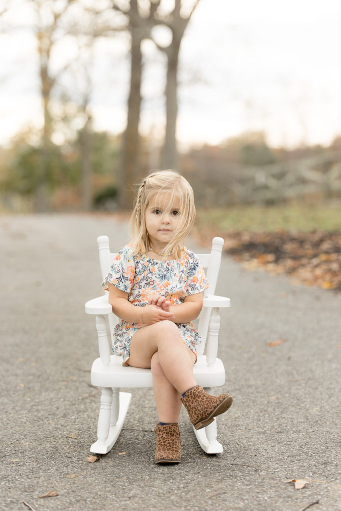 adorable toddler sits like an adult in white rocking chair