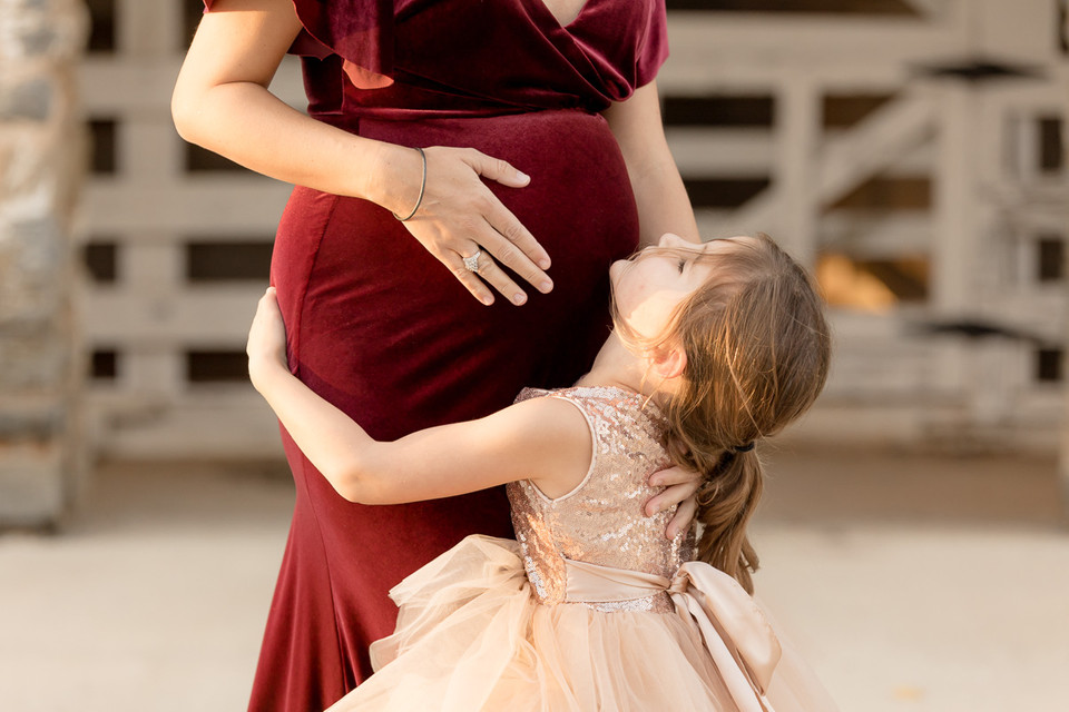 daughter hugs mom's pregnant belly