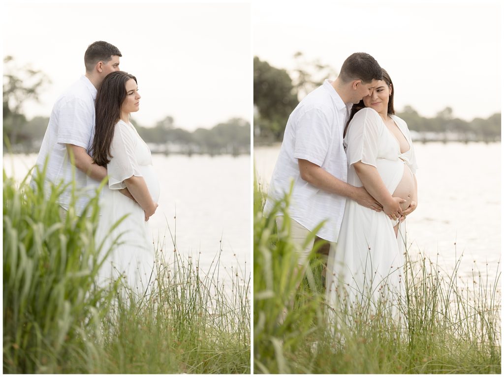 pregnant couple stands in tall grass at the beach