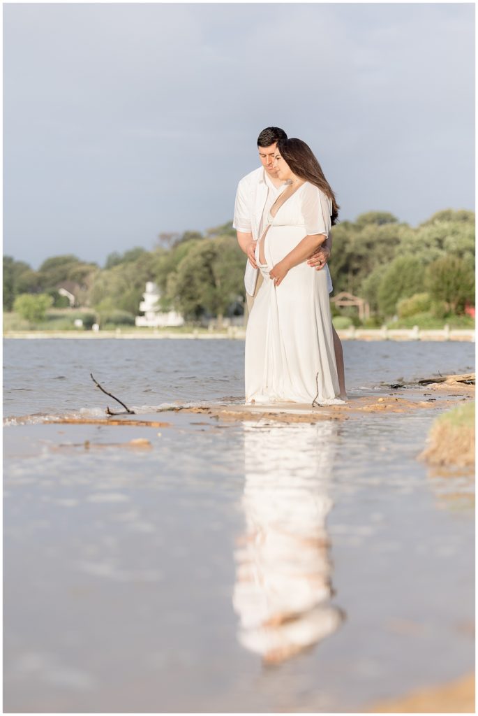 pregnant couple reflection in beach water