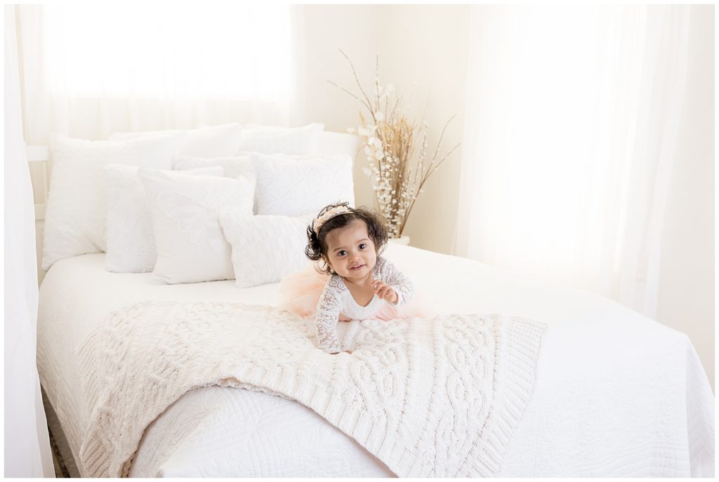 one year old baby crawls on white bed