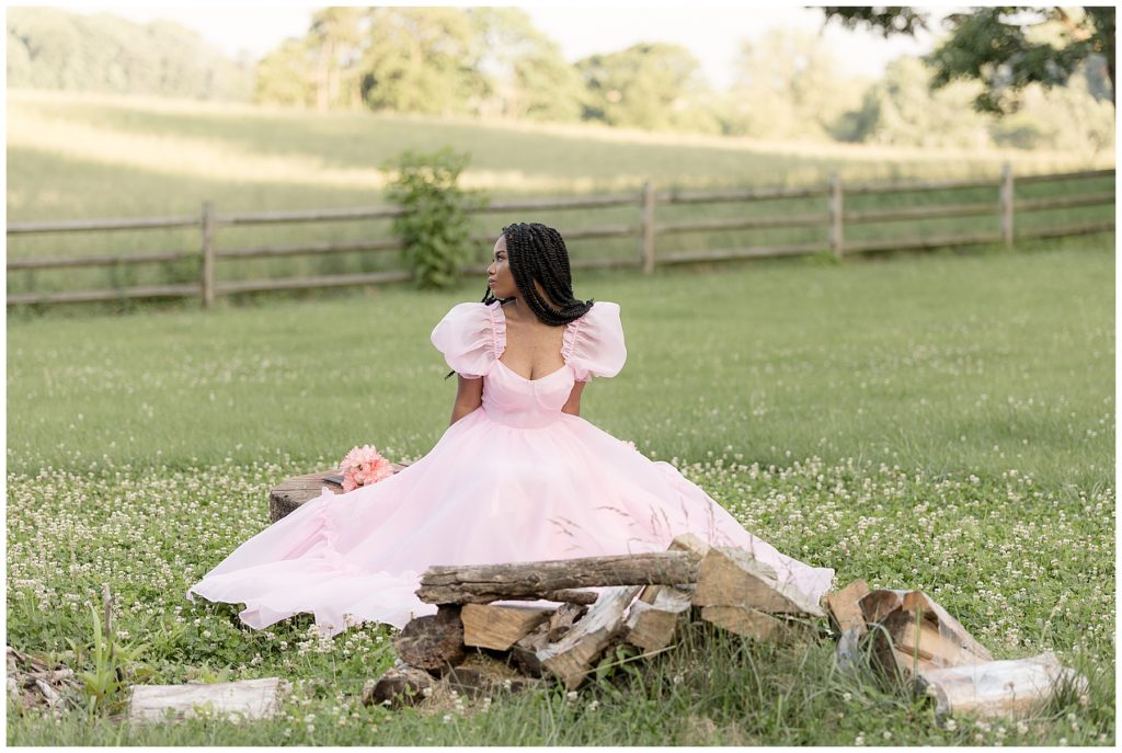 girl poses in field in pink poofy dress