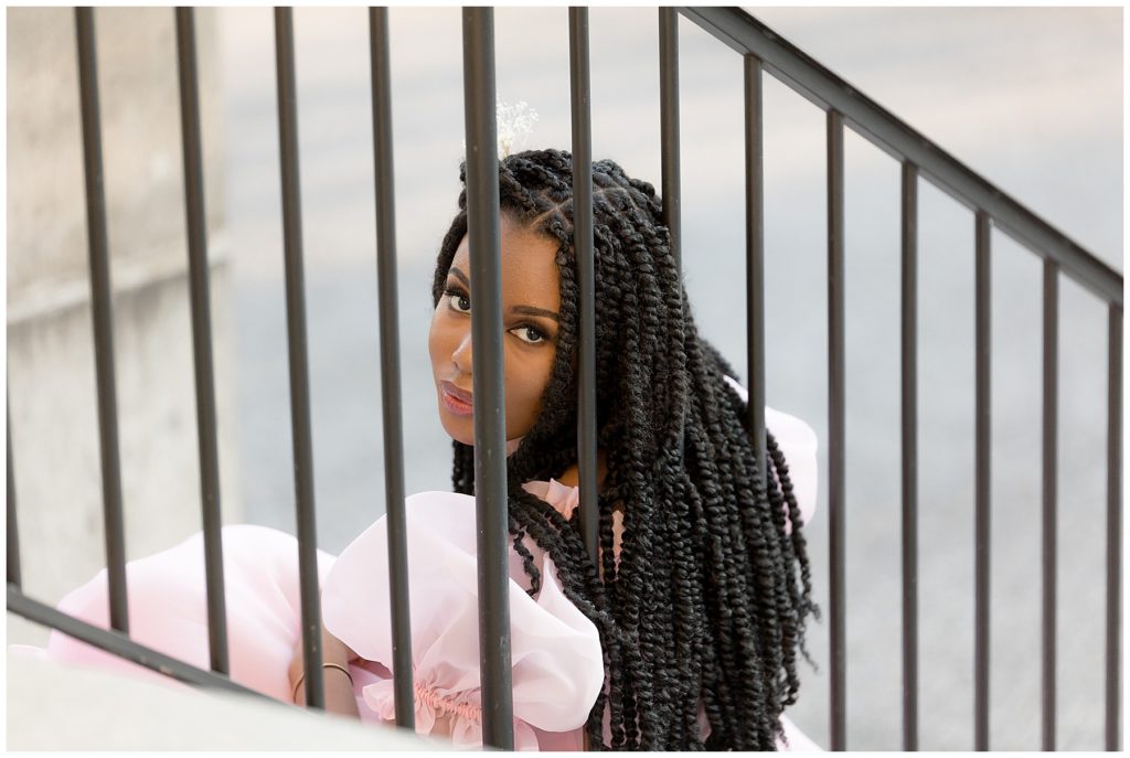girl peeks through iron railing at photographer
