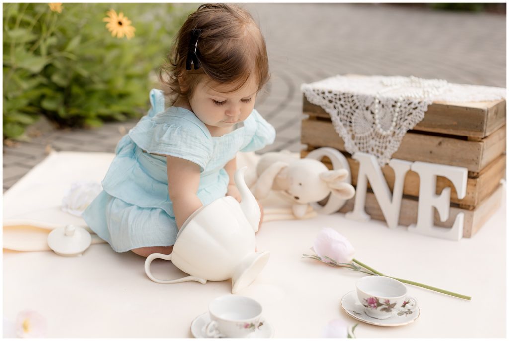 baby girl investigates tea pot