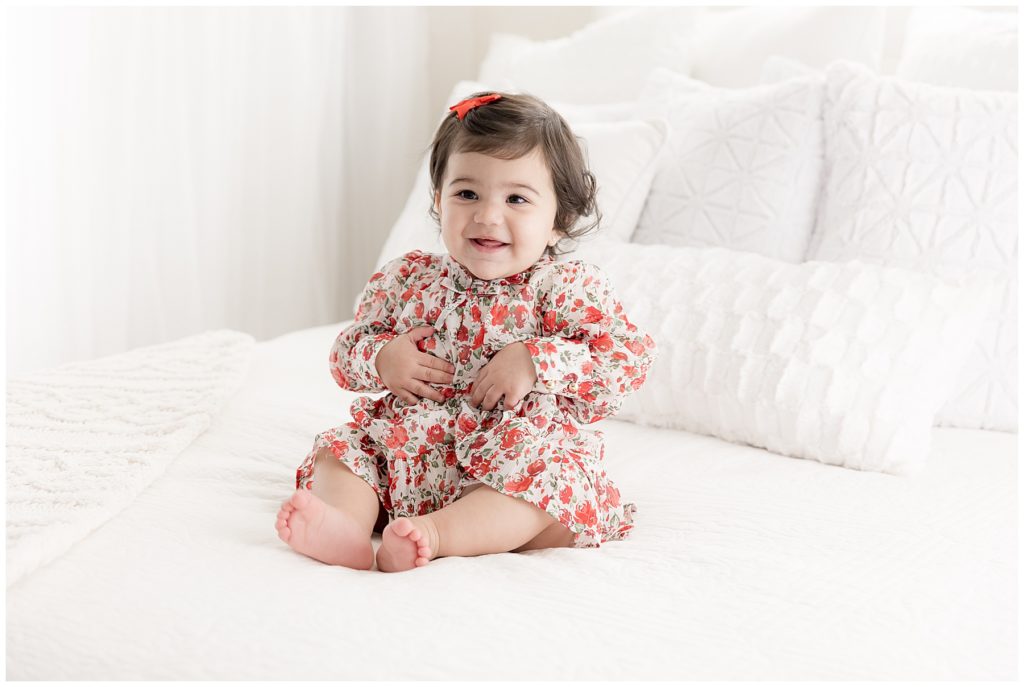 happy one year old baby in red flower dress