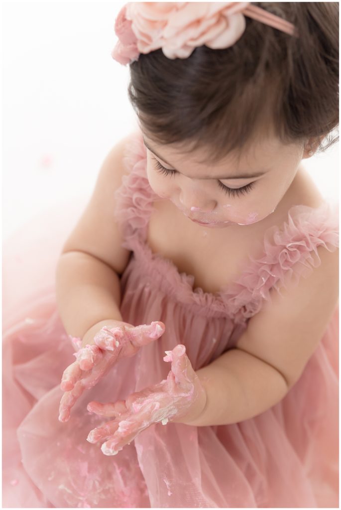 baby looks at cake covered hands