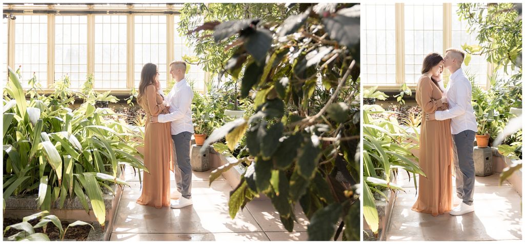husband tenderly embraces pregnant wife in greenhouse maternity photos
