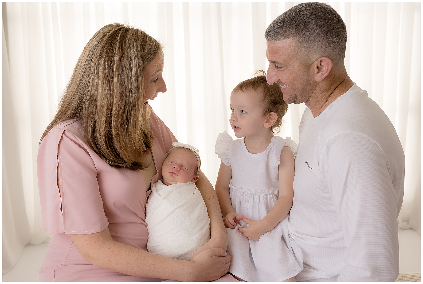 mom, dad, toddler, and newborn family posing