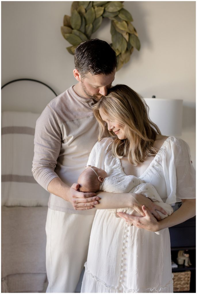 Studio or In Home Photos - couple holds newborn in front of bedroom window