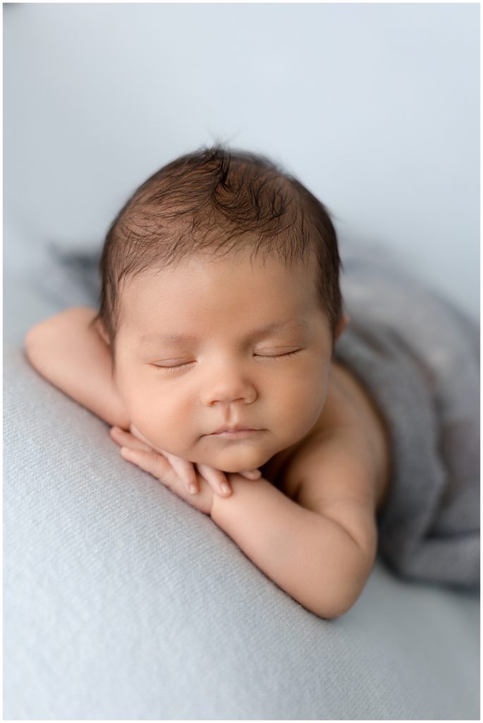 sleepy newborn boy on blue backdrop