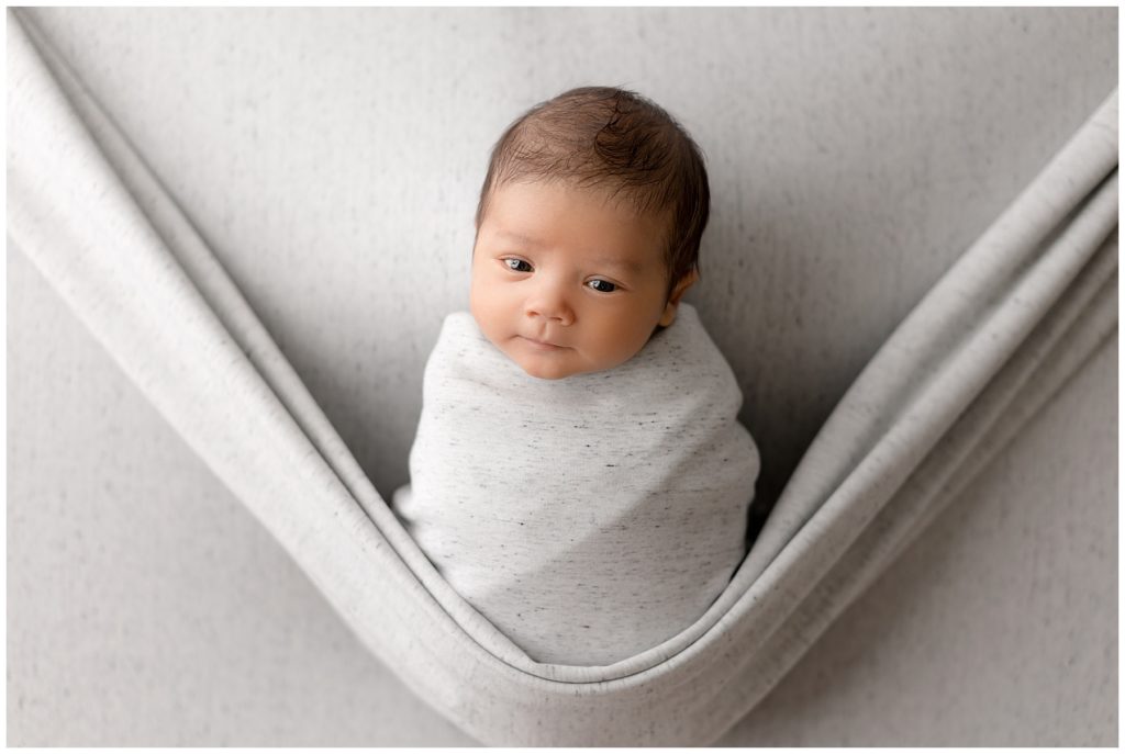 head tilted newborn looks at Maryland photographer