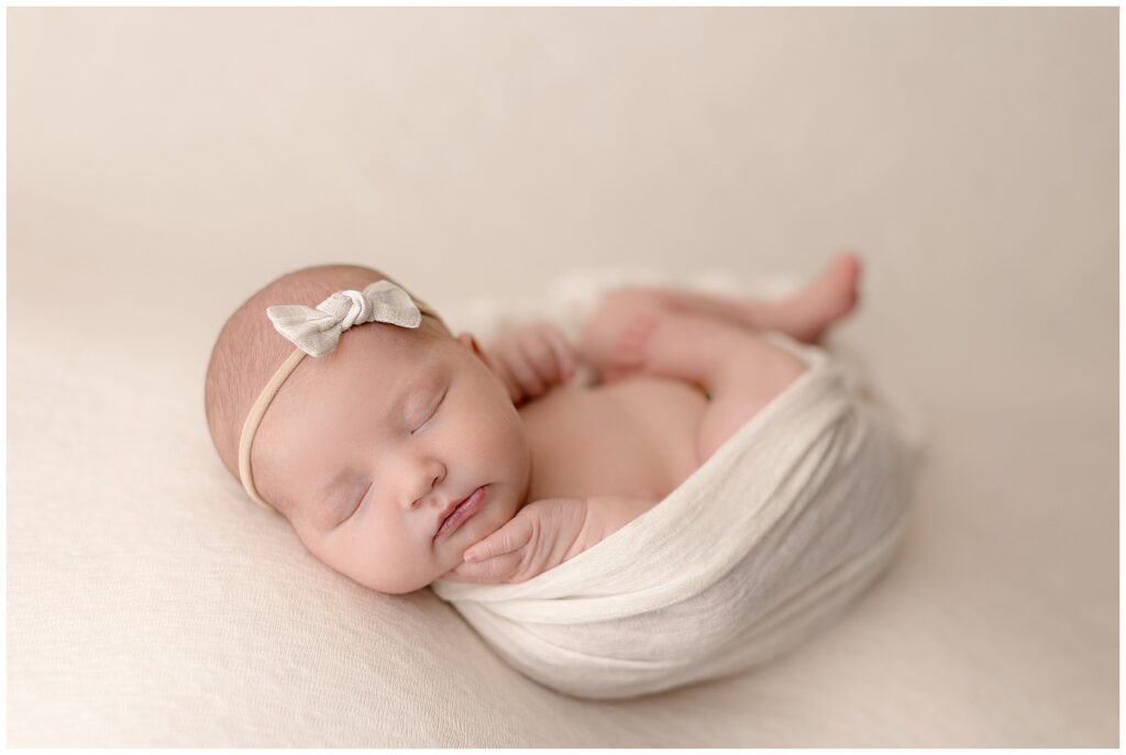 sweet newborn girl in cream with bow