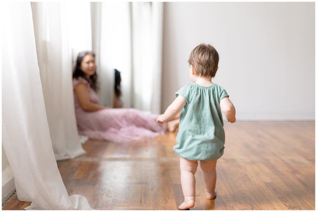 baby walks toward mom, showing the bond between a mother and child