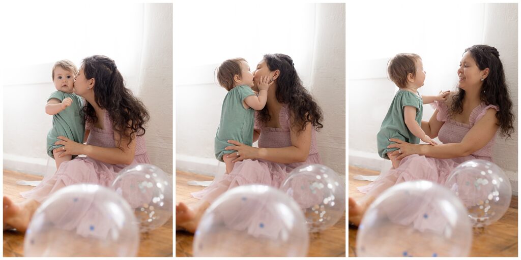 mom and baby snuggles surrounded by birthday balloons